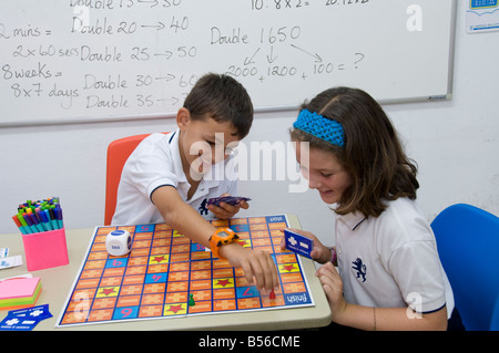 Junior Schüler im Klassenzimmer ein wettbewerbsfähiger mathematische Brettspiel hinzufügen, Subtraktion und Multiplikation. Stockfoto