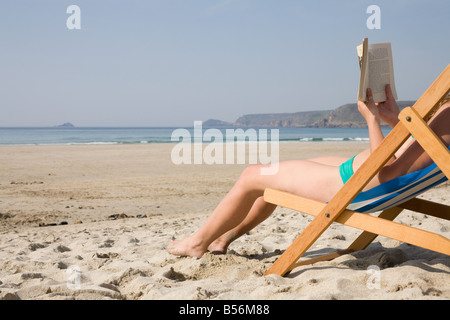 Frau liest ein Buch auf einem leeren Strand Stockfoto