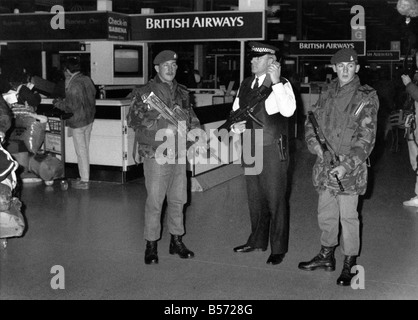 Soldaten mit Maschinengewehren Tand neben einem bewaffneten Polizisten als Sicherheit steigt am Flughafen Heathrow im Zuge der Golf-Frist vorbei. ; Januar 1991; P004602 Stockfoto