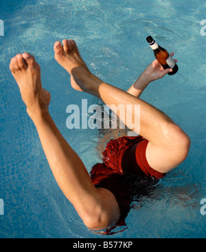 Junger Mann versucht einen einhändige Handstand in einem Pool mit gedrückter sein Bier. Spring Break, Spaß in der Sonne fühlen. Stockfoto