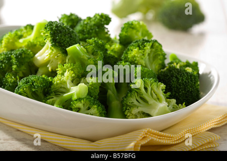 gekocht, Broccoli-Röschen in weiß Schüssel auf gelbe Geschirrtuch Stockfoto