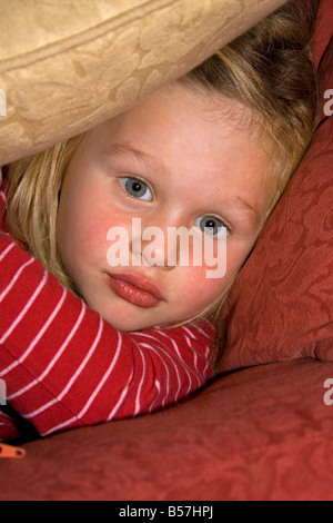 Junges Mädchen peeping Out hinter einem Kissen UK Stockfoto