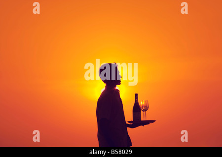 Kellner mit Tablett mit Flasche Wein und zwei Gläser bei Sonnenuntergang Stockfoto