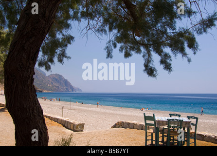 Eine Taverne Tisch mit Blick auf das Meer und Kiesstrand Strand in Sougia an der Südküste von Kreta, Griechenland, Europa Stockfoto