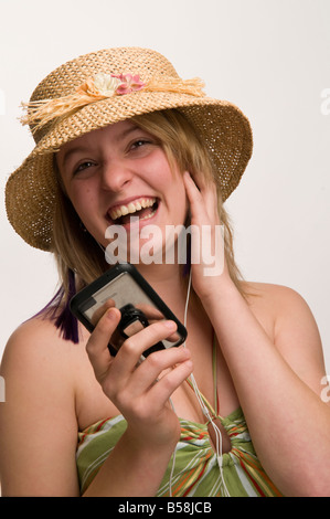 Glücklich lächelnde junge [Jugendliche] Frau mit Stroh Hut und Sommerkleidung anhören von Musik auf ihrem iPod touch Stockfoto