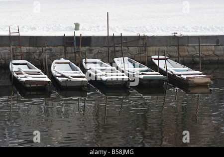 verschneite verlassene Fischerboote auf dem Fluss Stockfoto