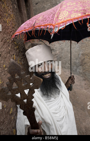 Ein Priester hält ein Kreuz an die Felsen gehauene Kirche von Bet Giyorgis (St. Georg), in Lalibela, Äthiopien, Afrika Stockfoto