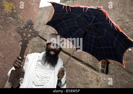 Ein Priester hält ein Kreuz an die Felsen gehauene Kirche von Bet Giyorgis (St. Georg), in Lalibela, Äthiopien, Afrika Stockfoto