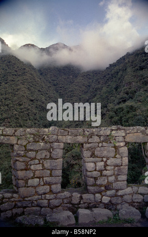 Panoramafotus der Morgenwolken, die die Berge hinter den Winay Wayna Ruinen auf dem Inka Trail in Peru bedeckten. Stockfoto