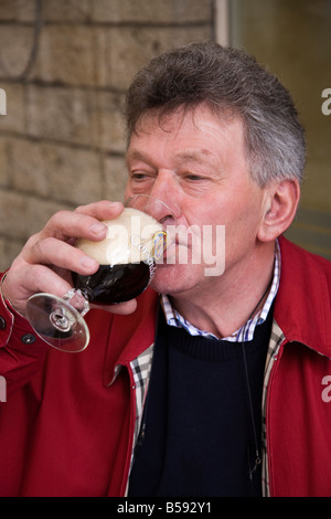 Mittleren gealterten männlichen Touristen nippt an ein belgisches Bier im Open-Air-Bereich einer Leuven-Bar. Belgien (42) Stockfoto