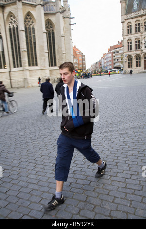 Junger Mann zu Fuß in Leuven, Belgien, mit seinem Arm in einer Schlinge. (42) Stockfoto