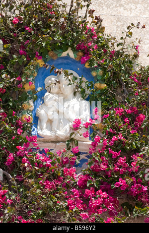 Madonna mit Kind umgeben von Bougainvillea Blumen an Hauswand in Mdina, Malta Stockfoto