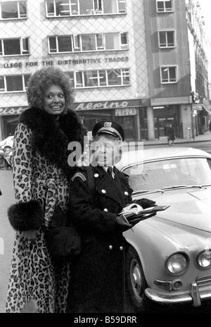 Modell Lorne Lesley trägt einen langen Leopard Hautmantel mit Pelzkragen hinter einem Traffic Warden; Februar 1975; 75-01140-006 Stockfoto