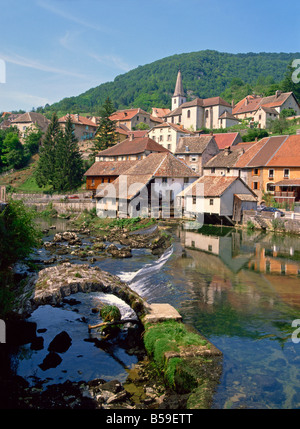 Die Wehr und die Überreste einer mittelalterlichen Brücke über den Fluss Loue, die Häuser und die Kirche des Dorfes Lods in Franche-Comte, Frankreich Stockfoto