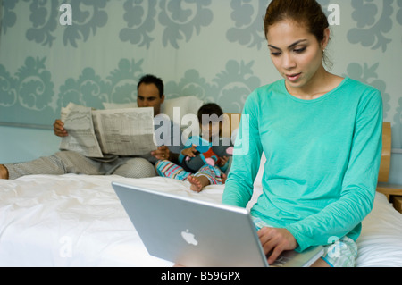 Familie auf dem Bett mit Zeitung und laptop Stockfoto