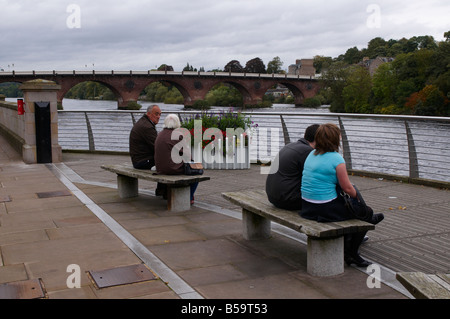 Junge und ältere paar sitzen auf Bank von Fluß Tay Perth Schottland UK Stockfoto