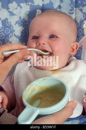 Erwachsene Hände Spoonfeeding glückliches junges baby Stockfoto