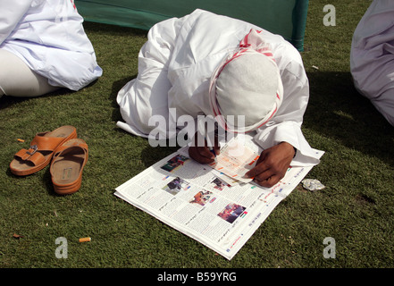 Man füllt in einem Wettschein bei der Nad Al Sheba Horse Race Course, Dubai, Vereinigte Arabische Emirate Stockfoto