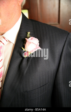 Der Bräutigam trägt ein weißes Knopfloch am Revers seines Anzugs auf einer Hochzeit. Stockfoto