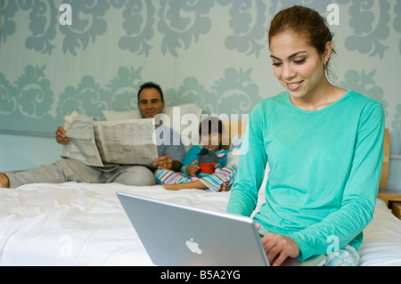 Familie auf dem Bett mit Zeitung und laptop Stockfoto