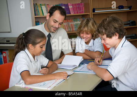 Kleine interaktive Studiengruppe glücklich junior SchülerInnen mit männlichen Lehrer in informellen Sprachkurs Stockfoto