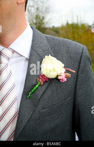 Der Bräutigam trägt ein weißes Knopfloch am Revers seines Anzugs auf einer Hochzeit. Stockfoto