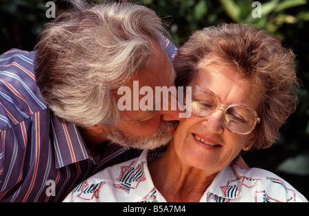 Mann küssen Frau zärtlich auf Wange im Garten Stockfoto