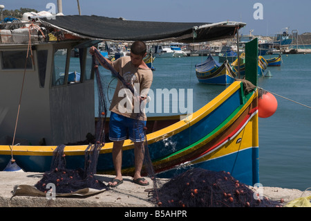 Das Fischernetz mit bunten Fischerbooten aussortieren Luzzus genannt, in Marsaxlokk, ein Fischerdorf, Malta Stockfoto