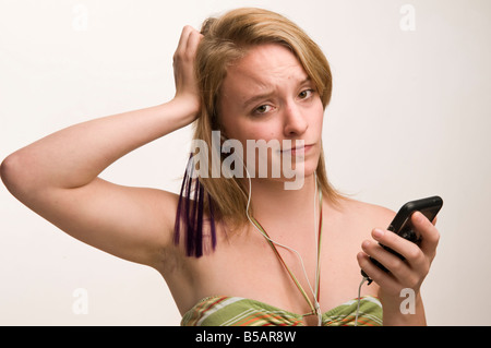 junge Frau Teenager-Mädchen anhören von Musik auf ihrem iPod Touch verwirrt durch die Technologie Stockfoto