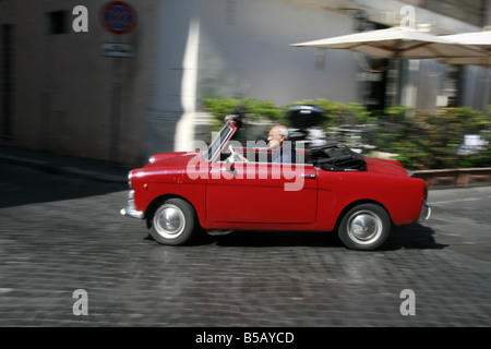 Alter Mann treibende klassische rote Oldtimer in Rom Stockfoto