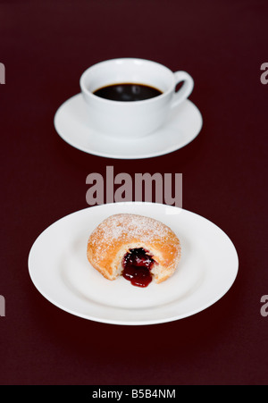 Kaffee Tasse und Marmelade Krapfen mit Biss Mark auf Platte Stockfoto