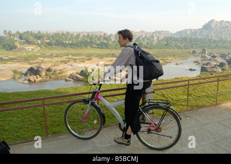 Deutsche weibliche Touristen auf gemieteten Fahrrad Aufsicht über den Fluss Tungabhadra. Indien, Karnataka, Hampi. Stockfoto