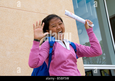 Teenager-Mädchen Student springt vor Freude außerhalb der Schule halten ihre ausgezeichnete Prüfungsergebnisse Stockfoto