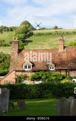 Landhaus in einem Dorf mit einer Windmühle auf dem Hügel im Hintergrund an einem sonnigen Tag hautnah Stockfoto