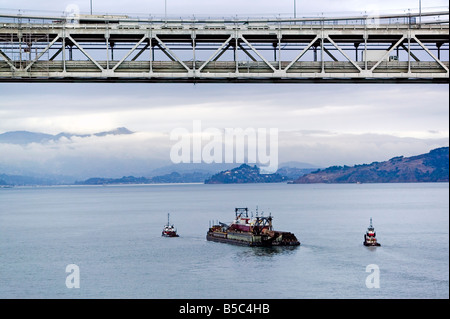 Luftaufnahme über Schlepper ziehen ein Lastkahn an der San Francisco Oakland Bay bridge Stockfoto