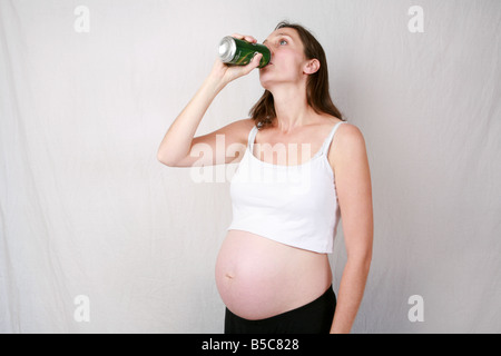 Hochschwangere junge Frau im dritten Trimester bei 32 Wochen Alkohol saufenden Fusel Bier Lager aus können stehend Stockfoto