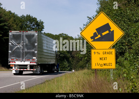 Sattelschlepper fährt vorbei ein Straße Zeichen Warnung Fahrer des steilen Hügel 9 % Steigung voraus Stockfoto