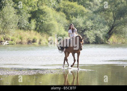 Teenager-Mädchen Reiten Reiten in einem flachen Flussbett Stockfoto