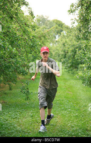 Teenager junge 15 Jahre alt läuft im Apfelgarten Stockfoto