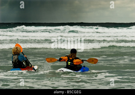 Zwei Surf-Kanuten paddeln Sie zum Meer als Schlechtwetter-Ansätze. Stockfoto