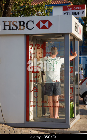 Ein Mann mit t-Shirt und Shorts in einer öffentlichen Telefonzelle in Hisaronu Türkei telefonieren Stockfoto