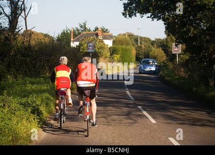 Aktive Erwachsene. Älteres paar Radfahren entlang einer Landstraße an der Grenze von Hampshire und Dorset. VEREINIGTES KÖNIGREICH. Stockfoto