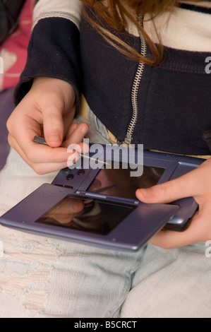 Teenager-Mädchen sitzen auf dem Sofa spielen Computerspiele auf Nintendo DS-Spiele-Konsole UK Stockfoto