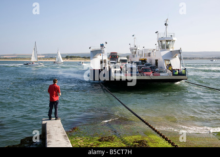 die Sandbänke Auto Fähre Studland Beach und ein Junge Angeln am belebten Eingang zum Hafen von Poole Stockfoto