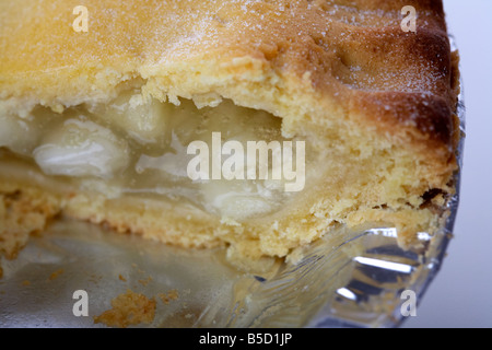 Nahaufnahme eines irischen Bramley Apfelkuchen Kuchen in Alufolie Platte Verpackung mit Scheibe herausgenommen Stockfoto