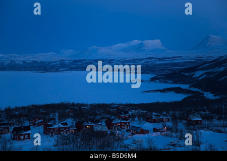 Am Abend fällt über dem kleinen Dorf Bjorkliden und das Eis bedeckt See Tornetrask in Lappland, Schweden Stockfoto