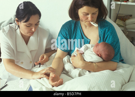 Hebamme macht einen Hausbesuch, eine neue Mutter und ihr Puls überprüfen Stockfoto