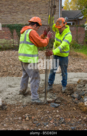 Arbeiter arbeiten die Stahlarmierung Balken hinunter in Betonpfähle. Stockfoto