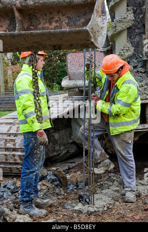 Arbeiter arbeiten die Stahlarmierung Balken hinunter in Betonpfähle. Stockfoto