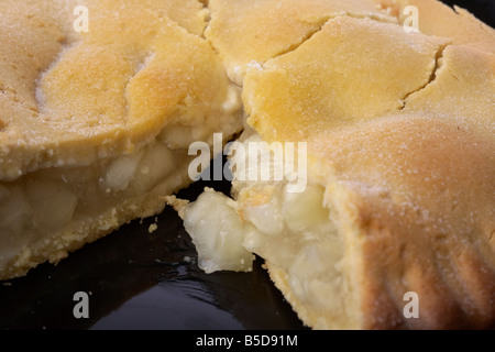 Nahaufnahme eines irischen Bramley Apfelkuchen Kuchen mit Scheibe auf einer schwarzen Platte herausgenommen Stockfoto